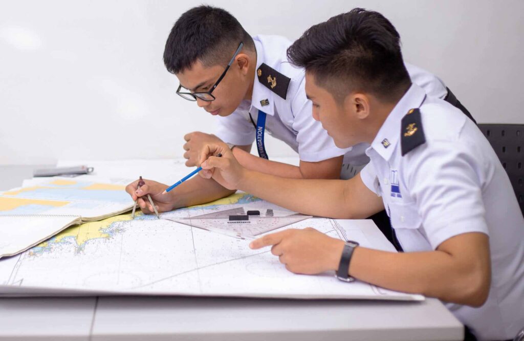 Young Marlow Navigation cadets gathered around a nautical chart and navigation tools during a training session.
